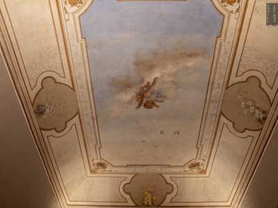 In una terza stanza ampie fasce bianche con bordure dorate, interrotte da ovali con fiori colorati, racchiudono uno sfondo celestiale...